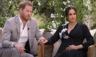 Prince Harry and Meghan Markle holding hands during an outdoor interview.