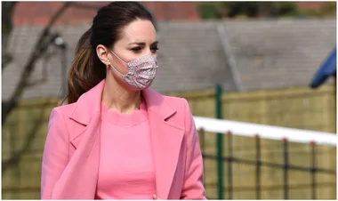 Woman in pink coat wearing floral mask, outdoors.