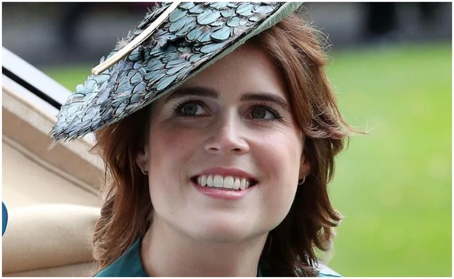 A woman smiling, wearing a feathered hat, outdoors with a blurred green background.
