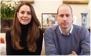Don't know who they are, but a woman in a black turtleneck and a man in a blue sweater are sitting on a sofa together.