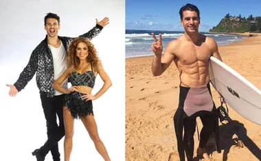 Two people in black sequined outfits pose; a man holding a surfboard on a sunny beach, making a peace sign.