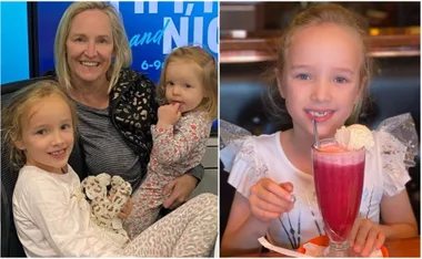 A mother with her two daughters smiling, and one daughter enjoying a pink milkshake with ice cream.