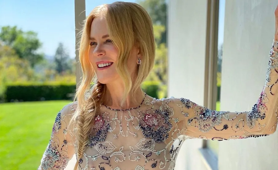 Nicole Kidman wearing a floral embellished sheer dress, smiling outdoors with long wavy blonde hair.
