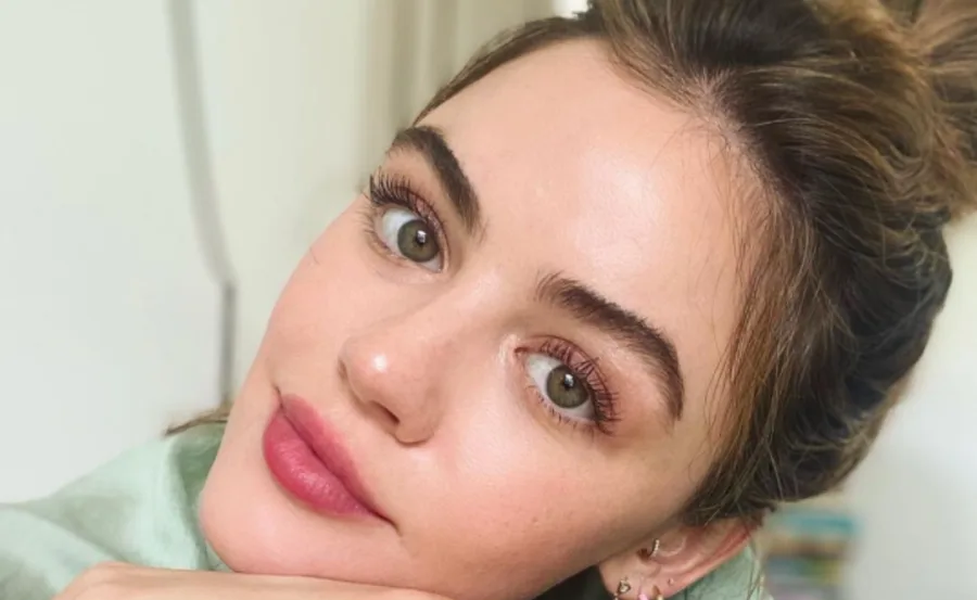 A person with laminated eyebrows, pink lips, and pulled-back hair looking into the camera.