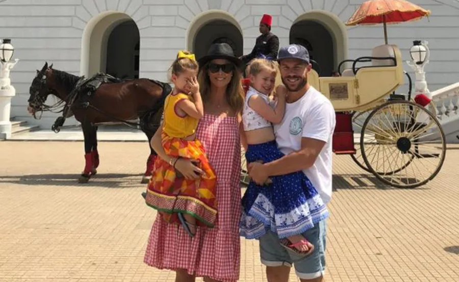 A family posing in front of a horse-drawn carriage with a guard in traditional attire at a historic building.