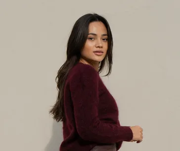 A woman in a burgundy sweater poses against a neutral background.