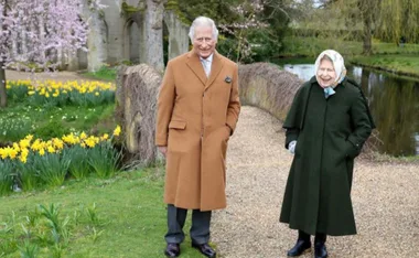 "Two people walking in a garden with daffodils and archway in the background."