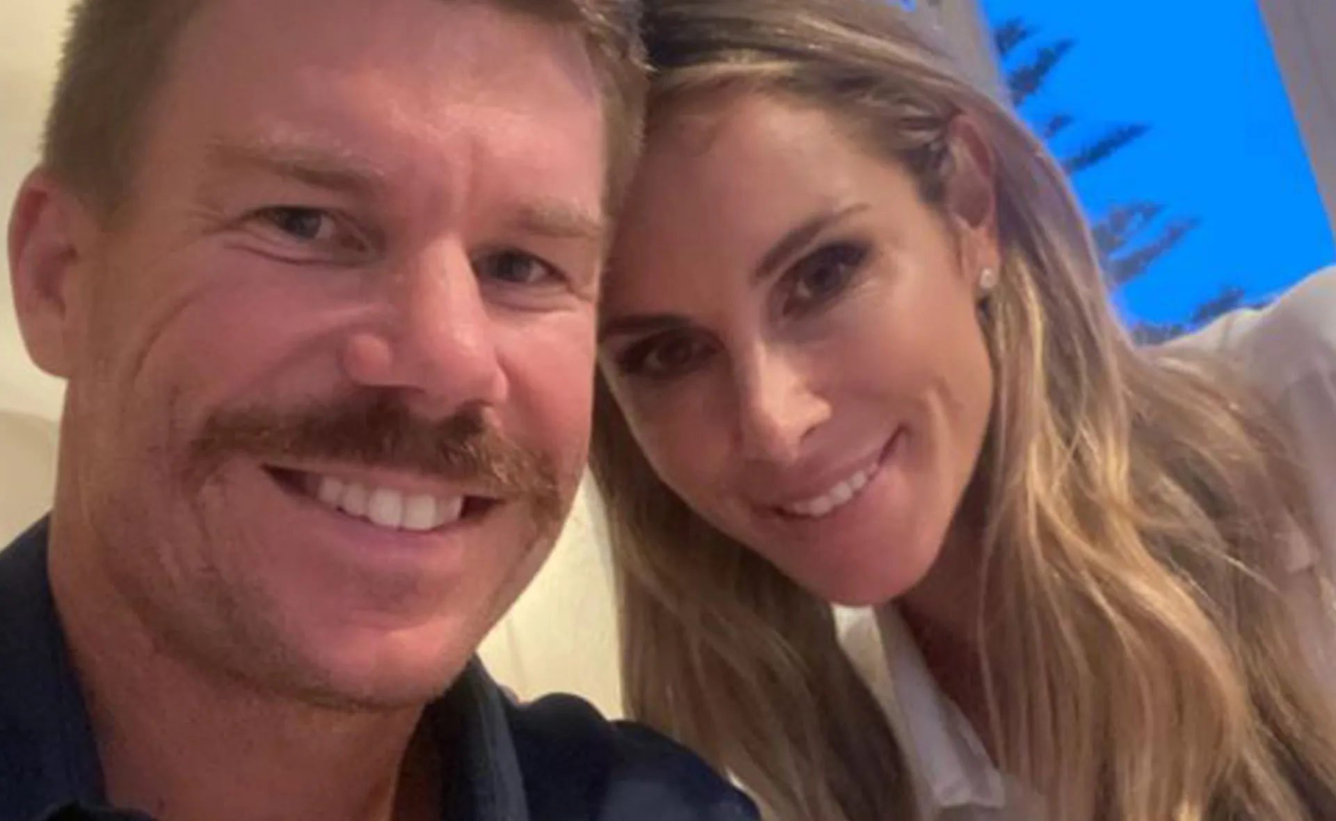 A smiling couple taking a close-up selfie indoors.