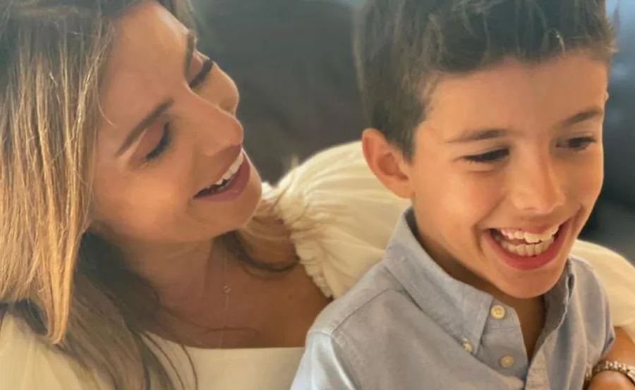 Smiling woman holding a young boy; both are laughing together.