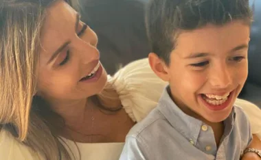 Smiling woman holding a young boy; both are laughing together.