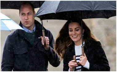A couple, holding umbrellas in the rain, walking and smiling at each other.