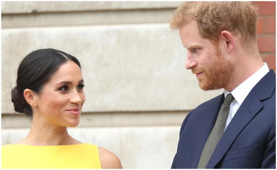 Two people smiling at each other, with one in a yellow dress and the other in a suit.