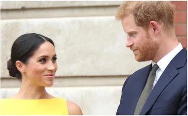 Two people smiling at each other, with one in a yellow dress and the other in a suit.