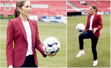 Woman in red blazer holding and juggling a soccer ball on a field.