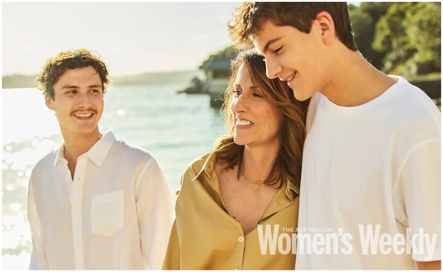 A woman and two young men smiling by the seaside, featured on a magazine cover.