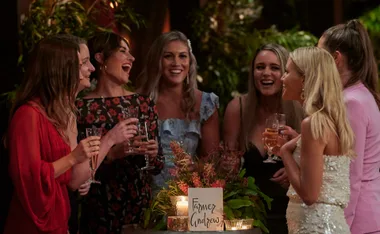 A group of women smiling and holding glasses, gathered around a table with a sign reading "Farmer Andrew."
