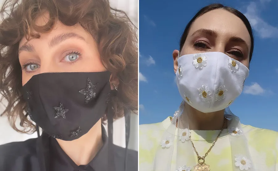 Two people wearing decorative face masks; one black with stars, the other white with floral design.