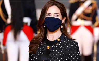 Princess Mary wearing a black mask and polka dot dress, pearl earrings, background with formal guards.