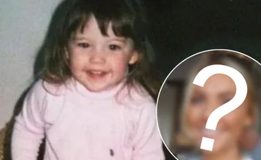 Young child in a pink sweater smiling with an obscured face overlayed with a question mark, suggesting a mystery identity.