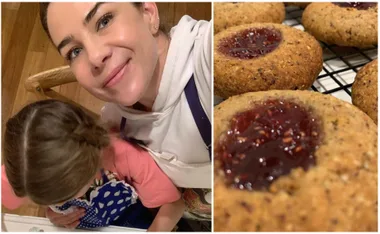 A woman and child baking together; freshly baked cookies with jam on a cooling rack.