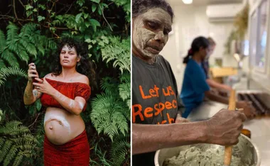 Pregnant woman in red with body paint stands in greenery; another person mixes substance in a bowl indoors.
