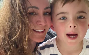 A woman with long hair is smiling with a young boy in a striped shirt.