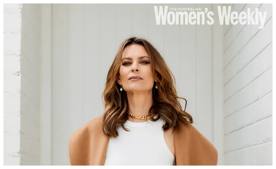 Woman posing confidently, wearing a white top and camel coat, featured in The Australian Women's Weekly magazine.