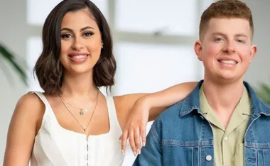 Two people smiling side by side; one in a white top and the other in a denim jacket.