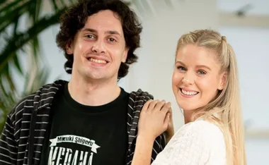 A man and woman smiling together in a casual indoor setting.