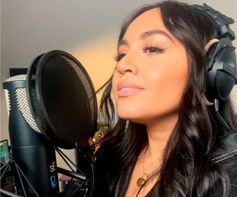 Singer with headphones recording in a studio, close-up side profile view.