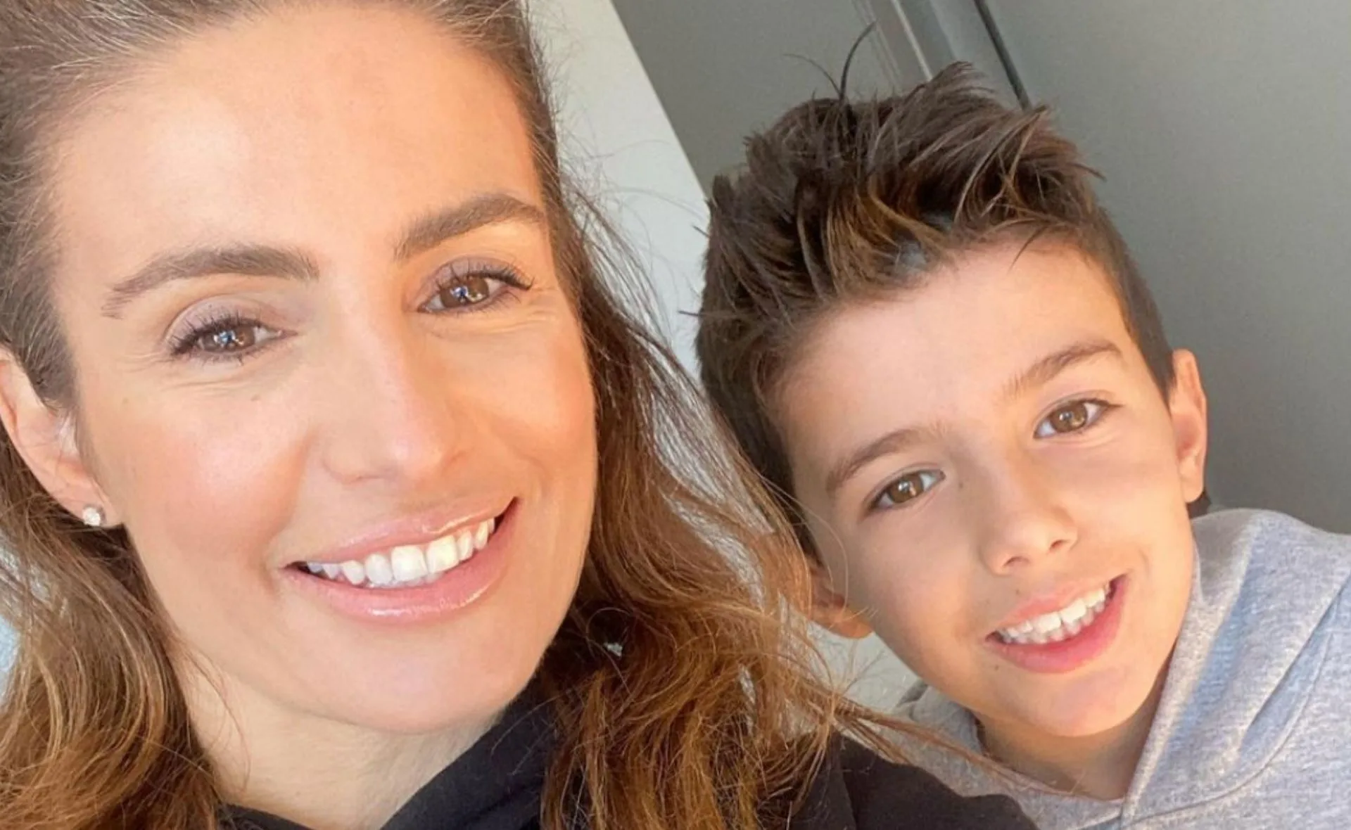 Smiling woman with long hair and a child with short hair, both looking at the camera.