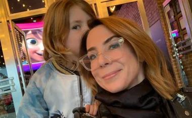 Woman and child taking a selfie outside a movie theater with an animated character on the screen.
