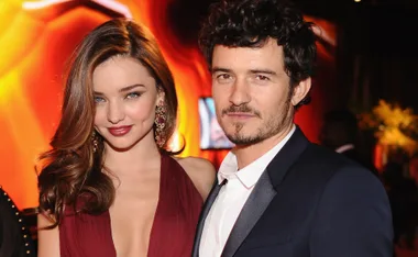 A couple posing together at a formal event with warm, elegant lighting in the background.
