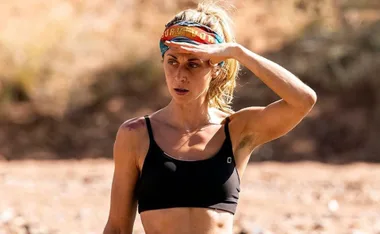 Person in athletic wear with a headband shielding eyes in a desert landscape.