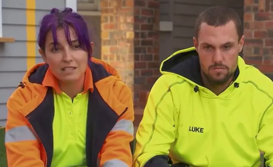 Two individuals in fluorescent workwear sitting outdoors; one with purple hair, the other with a hooded yellow top labeled "Luke."