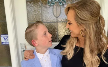 Woman and young boy smiling at each other in front of a glass door.