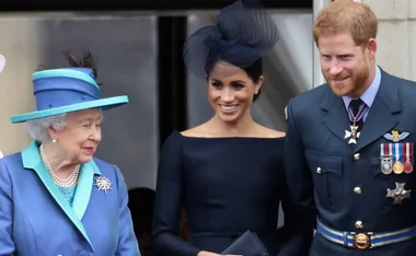 A royal family gathering with an elderly woman wearing a blue outfit and two younger adults in formal attire.
