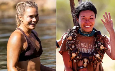 Two women smiling, one in a bikini by a lake, the other wearing tribal jewelry, outdoors in a sunny setting.