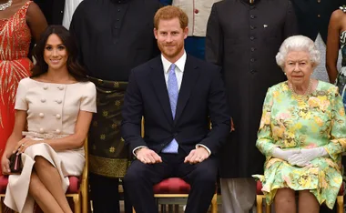 A seated group photo with individuals in formal attire, including a woman in a cream dress and a man in a suit.