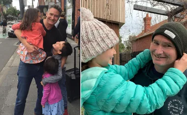 Man hugging three children on a city street; child adjusts his hat outdoors.