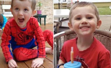 Young boy in a Spider-Man suit laughing and smiling at an outdoor setting.