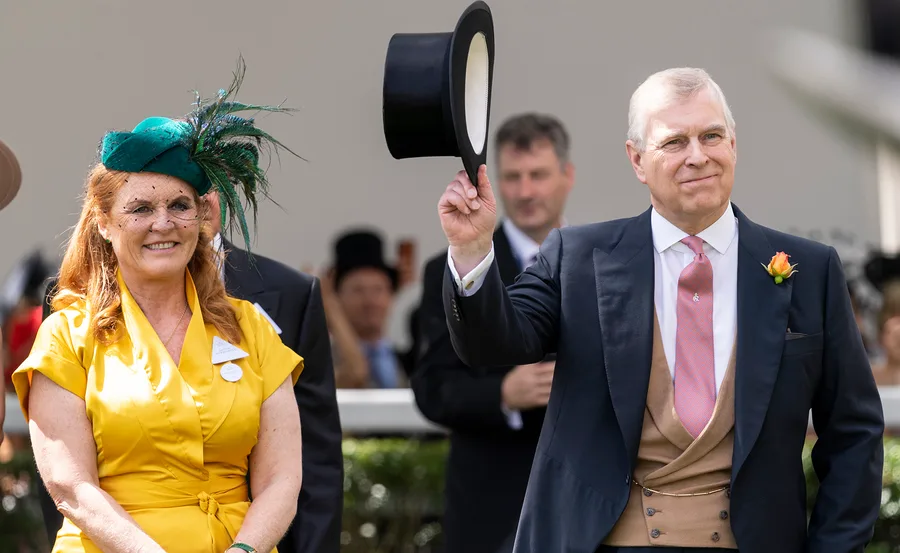 Man in suit holding a top hat, standing next to a smiling woman in a yellow dress with a green hat and veil.