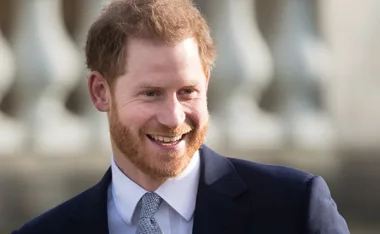 A man with red hair and a beard, smiling in a suit and tie outdoors.