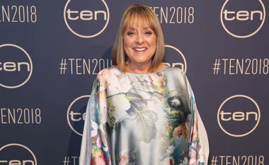 Person in floral dress at TEN2018 event backdrop, smiling.