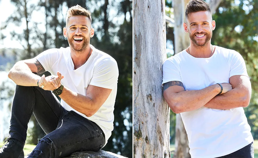 Man in a white T-shirt smiling outdoors; sitting and standing by a tree.