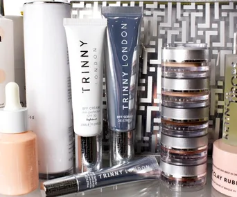Trinny London skincare products displayed on a shelf, including creams, serums, and stackable makeup pots.