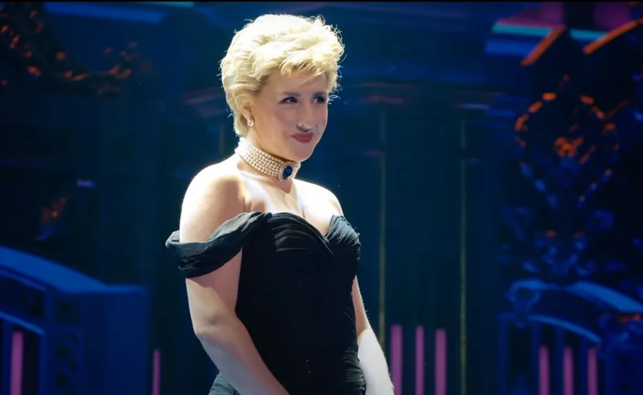 Actress in a black dress and pearl choker, performing on stage in the Princess Diana musical.