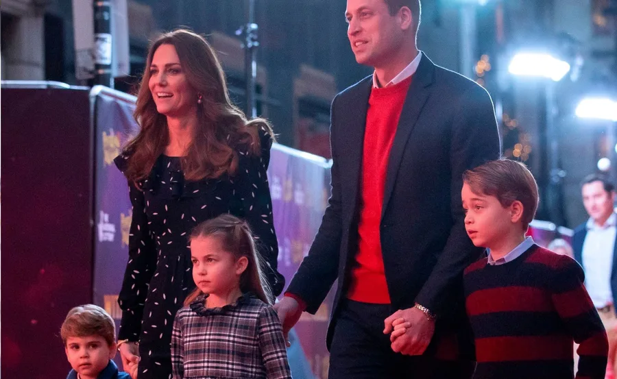 A family walking together on a lit path, holding hands and dressed in formal attire.