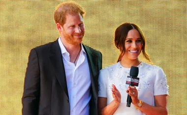 ```plaintext
Prince Harry and Meghan Markle on stage at Global Citizen Live event, both smiling and holding a microphone.
```