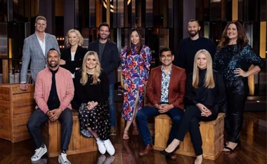Group photo of "MasterChef Australia 2021" judges and contestants on a wooden stage, smiling at the camera.